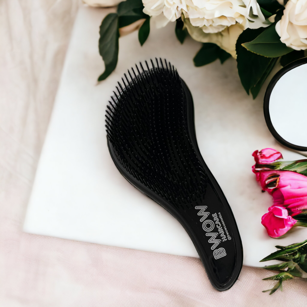 black hair brush by BWOW hair care on a pretty table with pink and white flowers